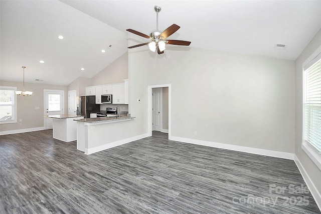 kitchen with white cabinetry, high vaulted ceiling, appliances with stainless steel finishes, kitchen peninsula, and ceiling fan with notable chandelier