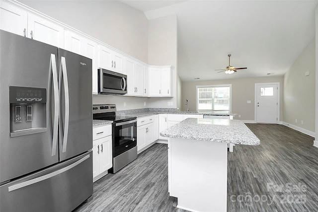 kitchen with appliances with stainless steel finishes, white cabinets, dark hardwood / wood-style flooring, a center island, and ceiling fan