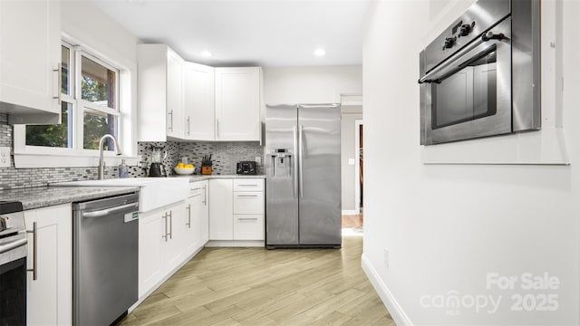 kitchen featuring decorative backsplash, white cabinets, light hardwood / wood-style floors, and appliances with stainless steel finishes