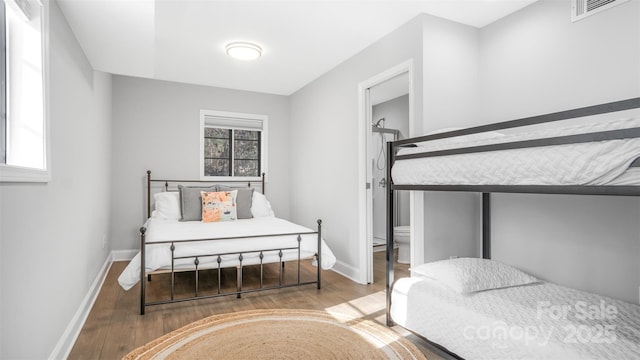 bedroom with wood-type flooring and ensuite bath