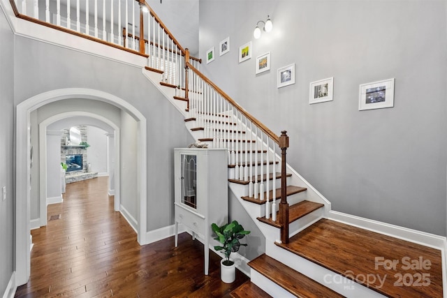 stairway with a towering ceiling and hardwood / wood-style flooring