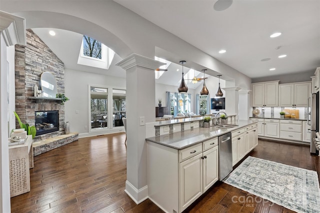 kitchen featuring dishwasher, a stone fireplace, sink, decorative light fixtures, and white cabinetry