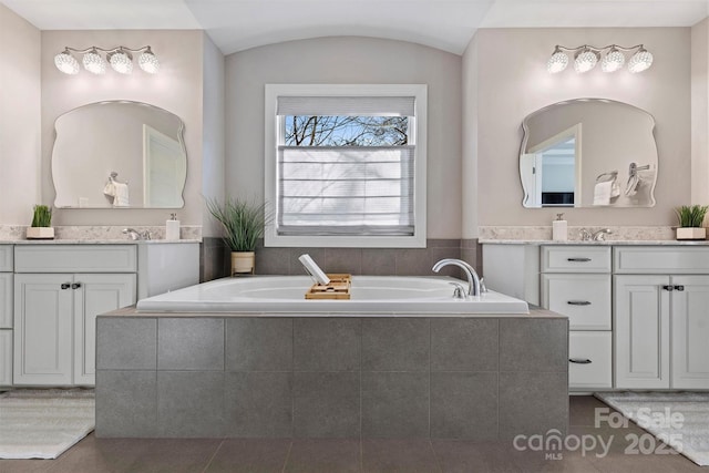 bathroom with tile patterned flooring, vanity, and a relaxing tiled tub