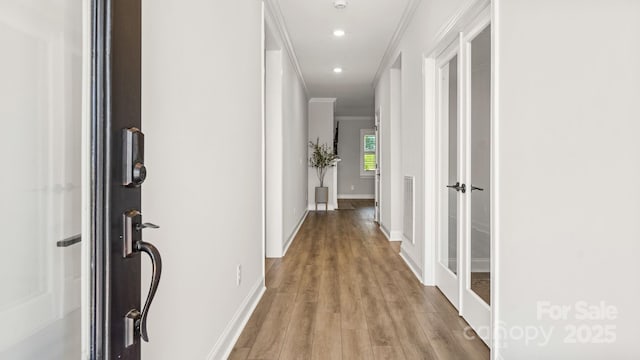 corridor featuring light wood-type flooring and crown molding