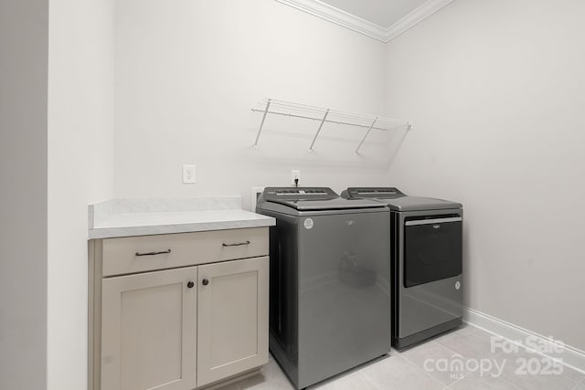 laundry area featuring cabinets, light tile patterned floors, washer and clothes dryer, and ornamental molding