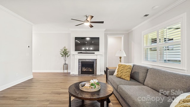 living room featuring ceiling fan, wood-type flooring, crown molding, and a high end fireplace