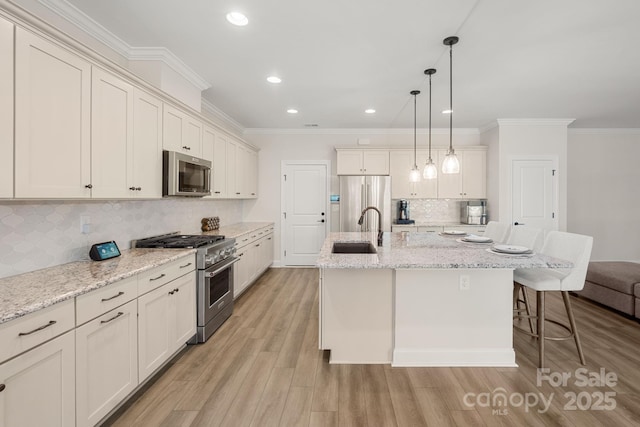 kitchen with pendant lighting, backsplash, a kitchen island with sink, sink, and appliances with stainless steel finishes