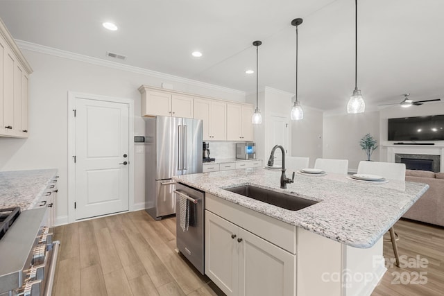 kitchen featuring ceiling fan, sink, hanging light fixtures, an island with sink, and appliances with stainless steel finishes