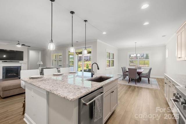 kitchen with a center island with sink, white cabinetry, hanging light fixtures, and sink