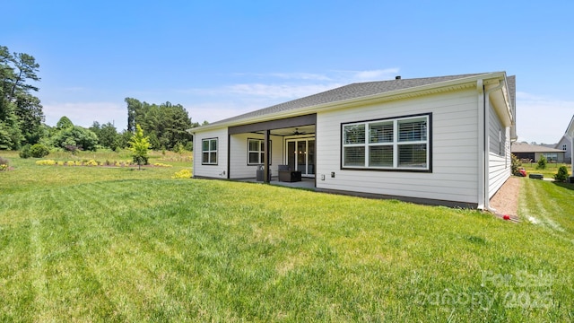 back of property with ceiling fan and a yard