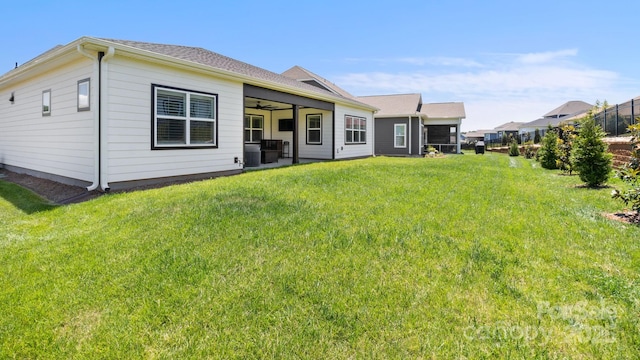 rear view of house featuring ceiling fan and a lawn