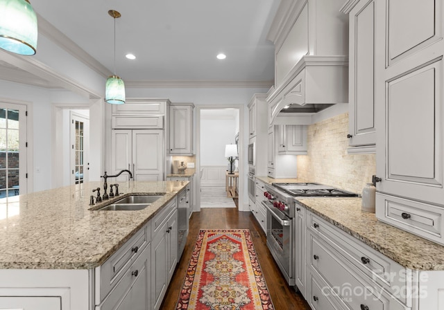 kitchen with sink, crown molding, a center island with sink, appliances with stainless steel finishes, and pendant lighting