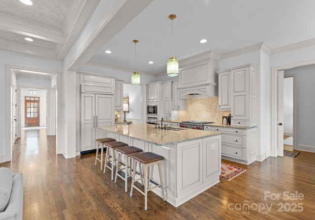 kitchen featuring decorative light fixtures, sink, a kitchen breakfast bar, a kitchen island with sink, and light stone countertops