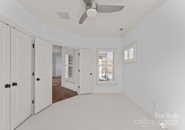 unfurnished bedroom with crown molding, ceiling fan, carpet flooring, and a closet