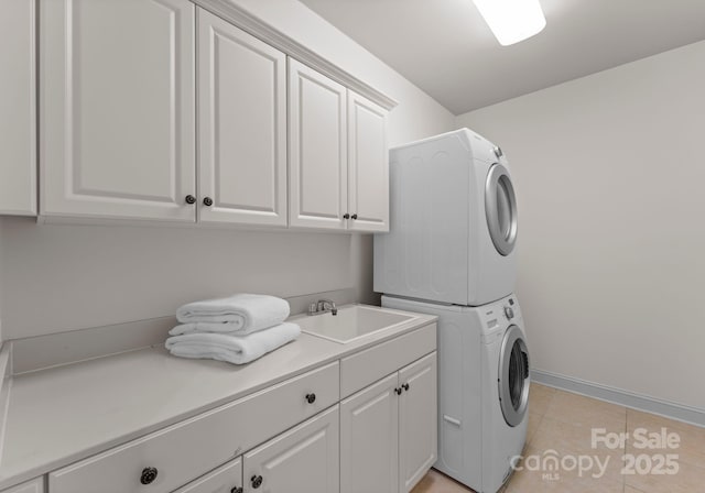 laundry room with cabinets, light tile patterned flooring, stacked washer and dryer, and sink