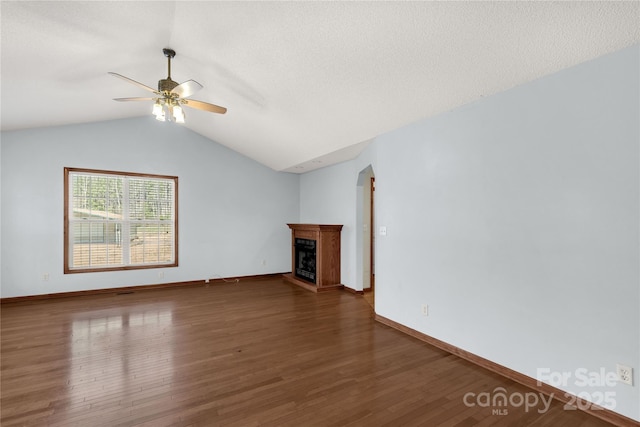 unfurnished living room with dark hardwood / wood-style floors, ceiling fan, and vaulted ceiling