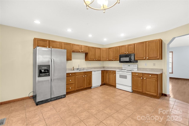 kitchen featuring light tile patterned flooring, white appliances, and sink