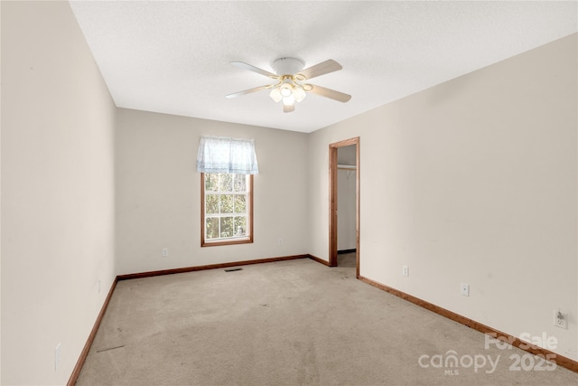 carpeted spare room with ceiling fan and a textured ceiling