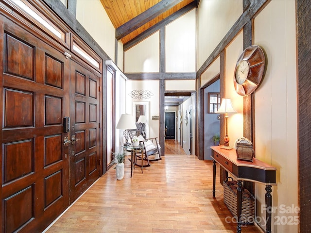 entrance foyer with beamed ceiling, light hardwood / wood-style flooring, high vaulted ceiling, and wooden ceiling