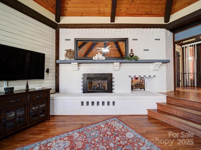 living room with hardwood / wood-style floors, vaulted ceiling with beams, a brick fireplace, and wood ceiling