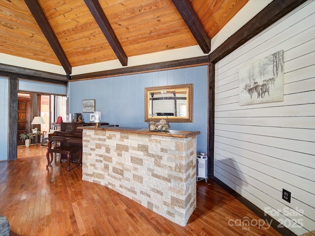 bar with lofted ceiling with beams, wood walls, wooden ceiling, and hardwood / wood-style flooring