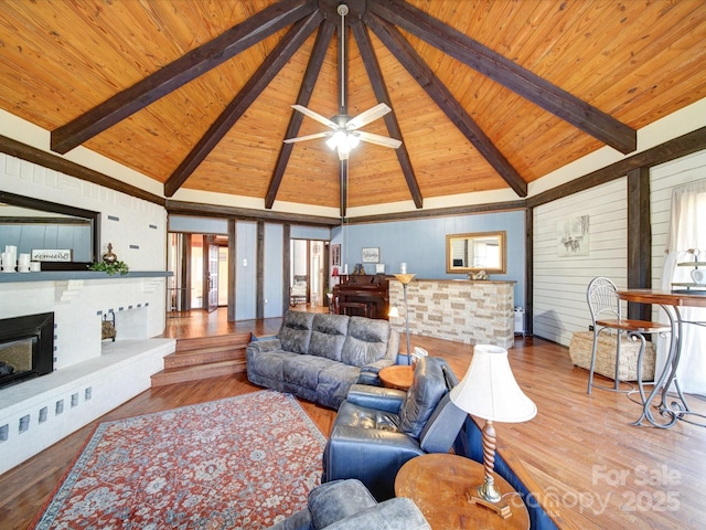 living room featuring beamed ceiling, wood-type flooring, wooden walls, and wood ceiling