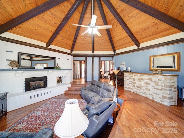 living room featuring beam ceiling, a brick fireplace, wooden ceiling, and hardwood / wood-style flooring