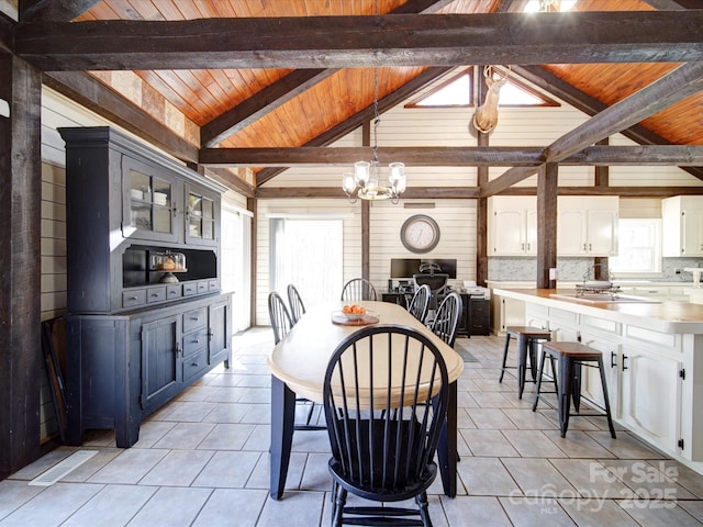 dining space with lofted ceiling with beams, sink, a notable chandelier, light tile patterned flooring, and wood ceiling