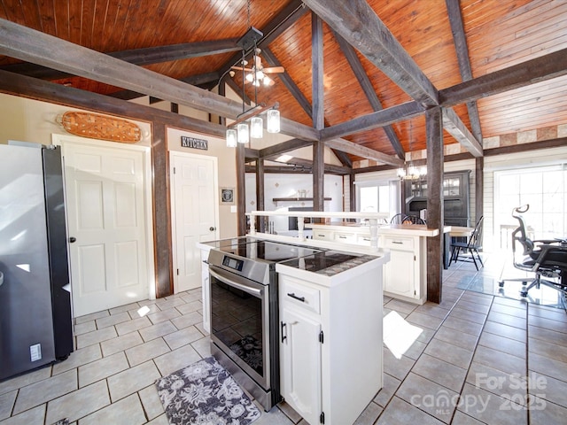 kitchen with white cabinets, a kitchen island, light tile patterned floors, and stainless steel appliances