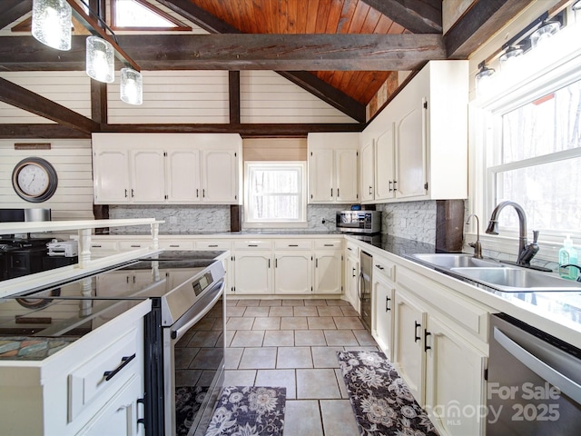 kitchen with sink, vaulted ceiling with beams, white cabinets, wood ceiling, and appliances with stainless steel finishes