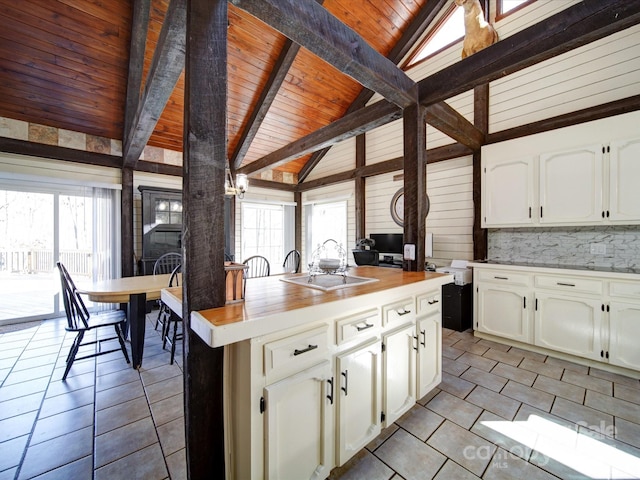 kitchen featuring wooden ceiling, sink, light tile patterned flooring, and lofted ceiling with beams