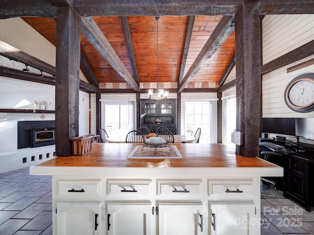 kitchen with butcher block countertops, white cabinetry, hanging light fixtures, and wood ceiling