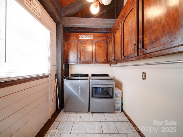 clothes washing area featuring washer and dryer, cabinets, wooden walls, light tile patterned flooring, and wood ceiling