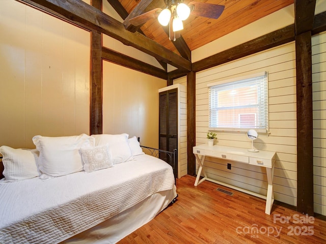 bedroom with light wood-type flooring, wood ceiling, vaulted ceiling, ceiling fan, and wood walls