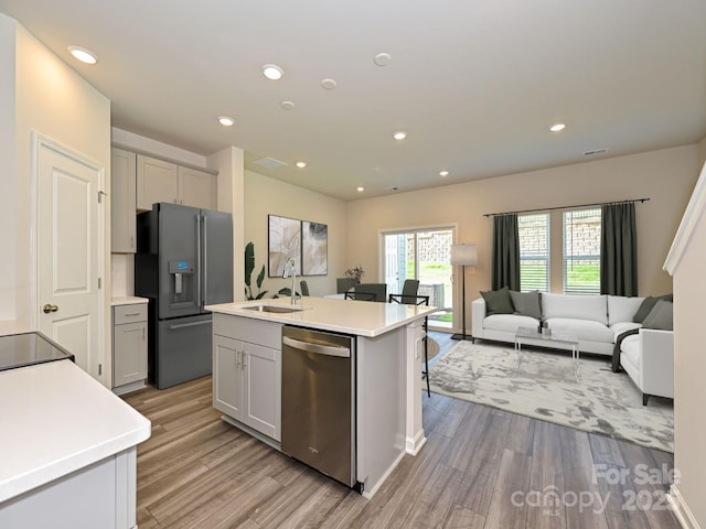 kitchen featuring gray cabinetry, stainless steel appliances, sink, a center island with sink, and light hardwood / wood-style floors