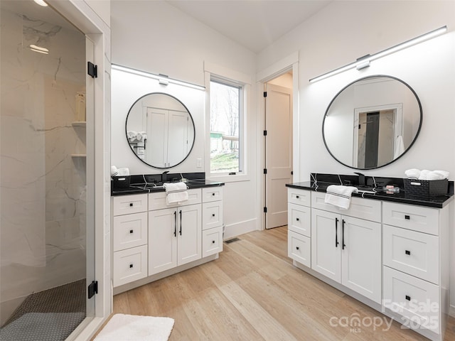 bathroom with hardwood / wood-style floors, vanity, and an enclosed shower