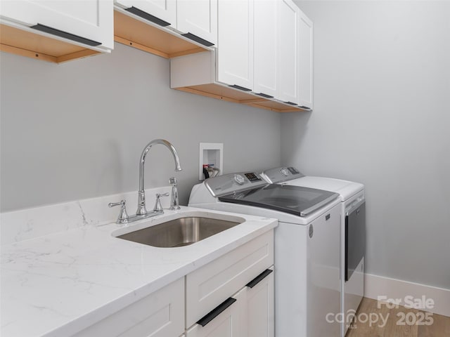 clothes washing area featuring washer and dryer, sink, and cabinets