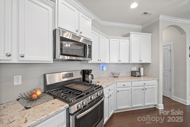 kitchen with white cabinets, light stone counters, crown molding, and appliances with stainless steel finishes