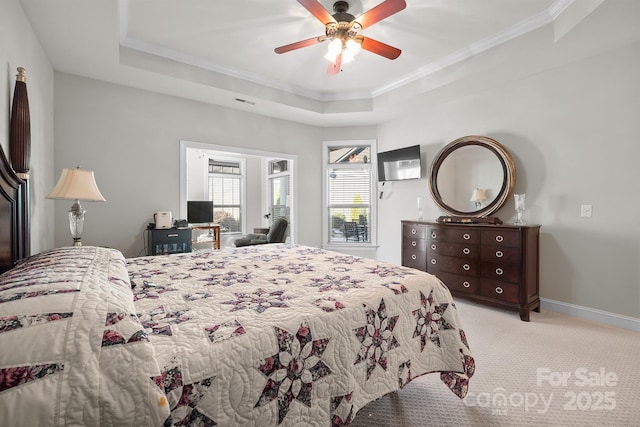 carpeted bedroom featuring ceiling fan, crown molding, and a tray ceiling