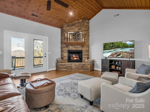 living room with wood ceiling, a stone fireplace, wood-type flooring, ceiling fan, and high vaulted ceiling