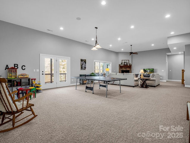 playroom with a towering ceiling, ceiling fan, and light carpet