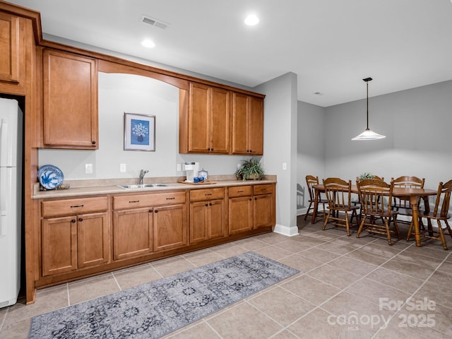 kitchen with white refrigerator, light tile patterned floors, pendant lighting, and sink