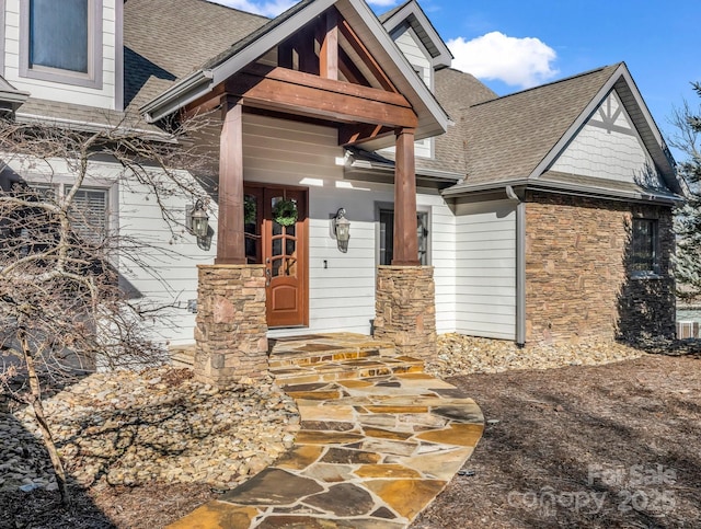 entrance to property with a shingled roof and stone siding