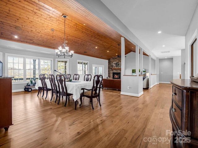 dining room with wooden ceiling, vaulted ceiling, a stone fireplace, light wood-type flooring, and recessed lighting