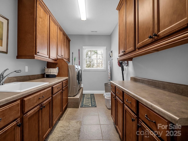 washroom featuring light tile patterned flooring, separate washer and dryer, a sink, baseboards, and cabinet space