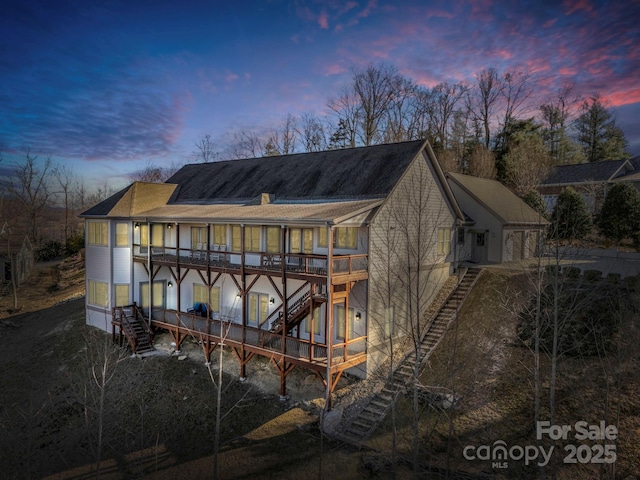 back of property at dusk featuring stairs, a chimney, and a wooden deck