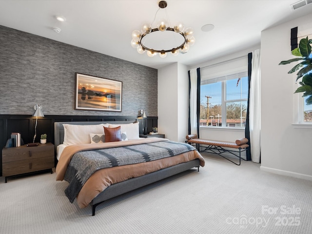 carpeted bedroom featuring an accent wall, a chandelier, visible vents, and baseboards