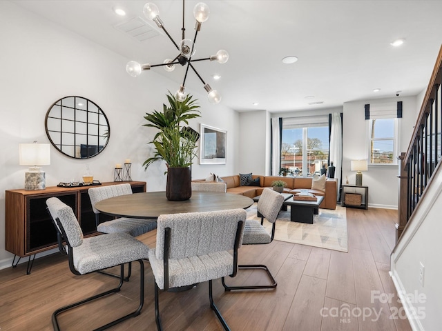 dining space with a notable chandelier, recessed lighting, stairway, light wood-type flooring, and baseboards