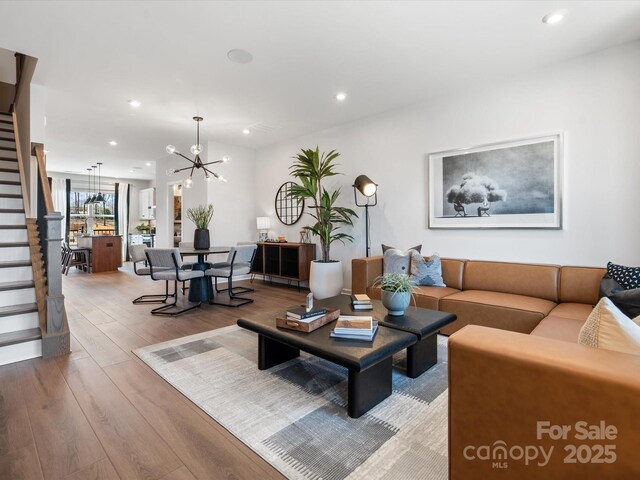 living area featuring stairs, a chandelier, hardwood / wood-style floors, and recessed lighting