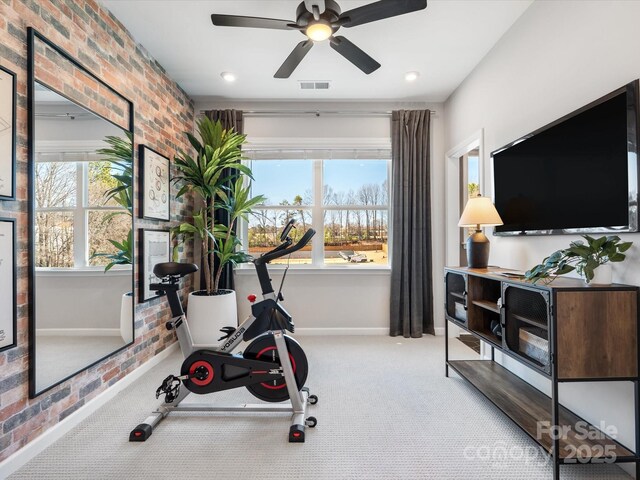 exercise room featuring carpet floors, visible vents, ceiling fan, brick wall, and baseboards